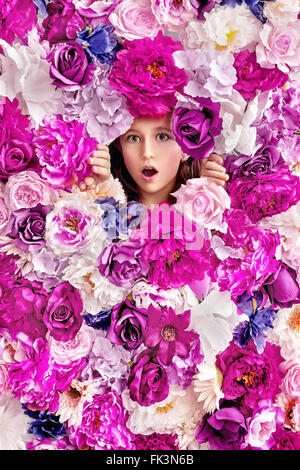 Surprised little girl behind a flower wall Stock Photo