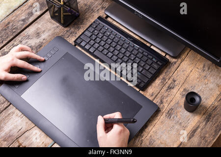 Workplace of graphic designer on wooden table. Artist drawing on graphic tablet at the desk. Overhead view image Stock Photo