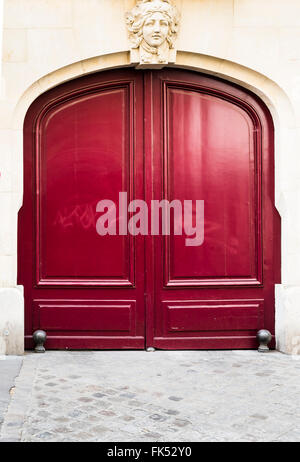 red wooden door, stone relief showing the head of a female figure Stock Photo