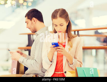 couple with smartphones and shopping bags in mall Stock Photo