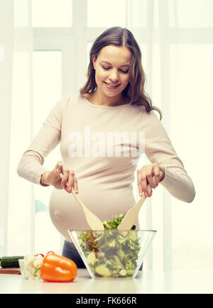 happy pregnant woman preparing food at home Stock Photo