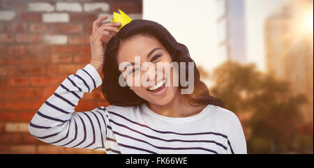 Composite image of smiling asian woman with paper crown Stock Photo