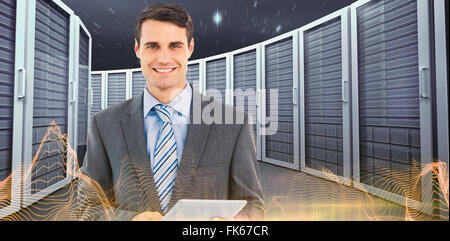 Composite image of businessman using a tablet  with colleagues behind in office Stock Photo