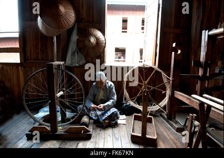 Woman spinning silk thread on a spinning wheel with bicycle wheel, Ko Than hlaing Weaving, Inpawkhan, Inle Lake, Shan state Stock Photo