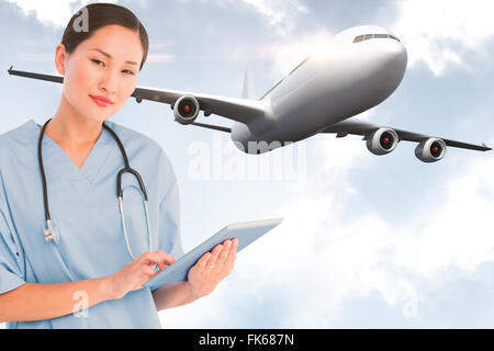 Composite image of surgeon using digital tablet with group around table in hospital Stock Photo