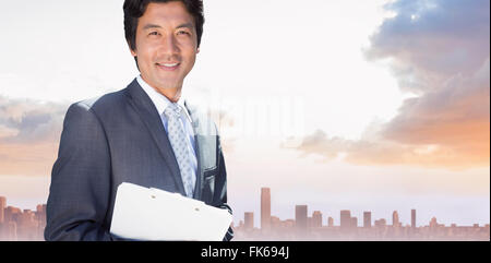 Composite image of confident estate agent standing at front door with clipboard Stock Photo