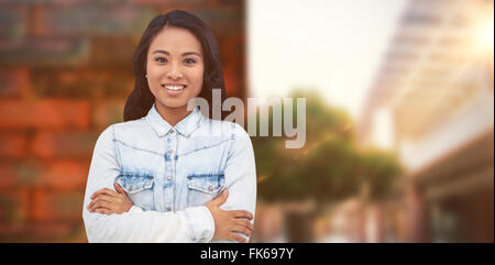 Composite image of asian woman with arms crossed smiling Stock Photo