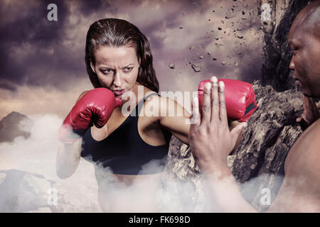 Composite image of female boxer practicing with trainer Stock Photo