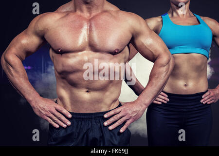 Composite image of midsection of muscular man and woman standing with hands on hip Stock Photo