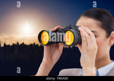 Composite image of brunette businesswoman looking through binoculars Stock Photo