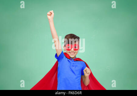 boy in red superhero cape and mask showing fists