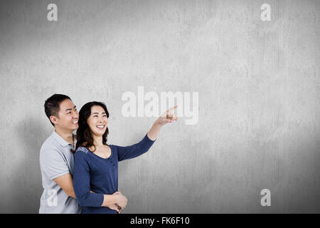 Composite image of happy couple with woman pointing up Stock Photo