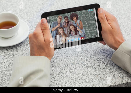 Composite image of businessman holding small tablet at table Stock Photo