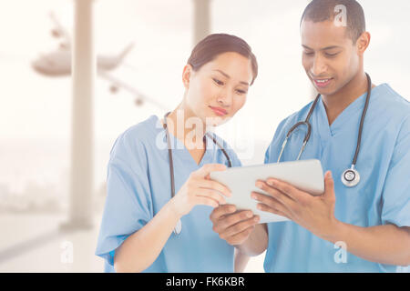 Composite image of surgeons looking at digital tablet in hospital Stock Photo