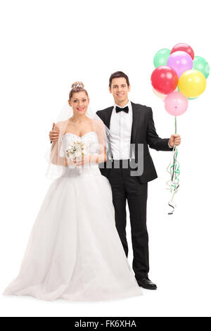 Full length portrait of a young newlywed couple holding a bunch of balloons and posing together isolated on white background Stock Photo