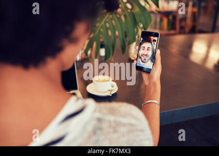 Young an and woman talking to each other through a video call on a smartphone. Young woman having a videochat with man on mobile Stock Photo