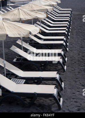 White empty sunbeds on black volcanic lava sand, early morning in Alcala Tenerife Canary Islands Spain Stock Photo