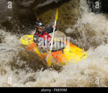 A kayak on the river Tawe at  Craig-y-Nos Country Park.  The kayak has just passed over a weir into the white water below. Stock Photo