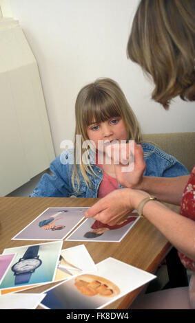 Speech therapist and young girl in therapy room using sign language Stock Photo