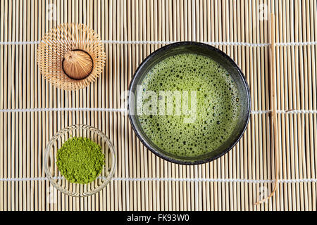 Green matcha tea with bubbles above view with whisk and powder and spoon Stock Photo