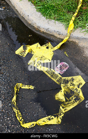 Police Line 'do not cross' tape torn down and discarded in the street Stock Photo