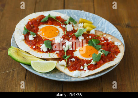 Breakfast with fried egg and sauce on grilled tortilla, Mexicanhuevos rancheros Stock Photo