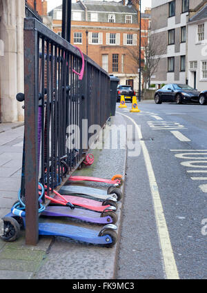 London, UK - 24 February 2016: Children's scooters secured to railings outside a school. St George's School Mayfair Stock Photo