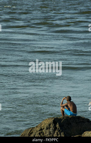 Boy contemplating the sea at Ponta do xareu - Cocoa Coast Stock Photo