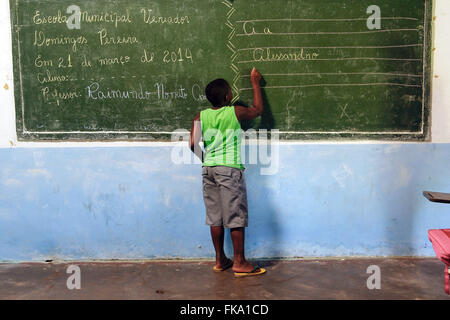 Student writing on the blackboard in the classroom of Escola Municipal Councilman Manuel Domingos Pereira Stock Photo