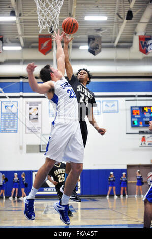 Defender extending in an effort to block a shot from just under the hoop during a high school basketball game. USA. Stock Photo