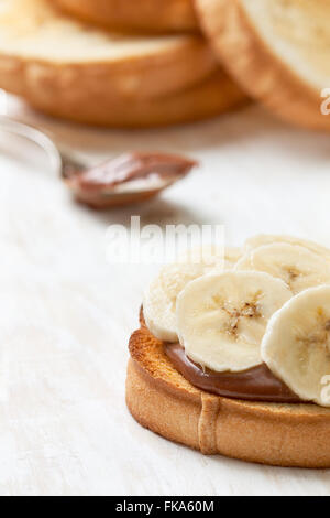 breakfast toast with banana and chocolate cream on a white wooden background Stock Photo