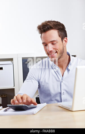 Happy Business man with laptop using calculator Stock Photo