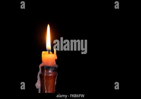 Single wax candle flame burning in darkness. Stock Photo