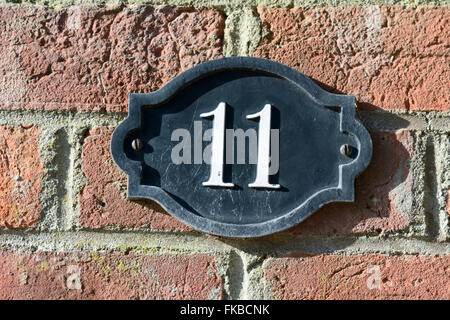 House number 11 sign on brick wall Stock Photo