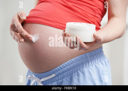 Close Up Of Pregnant Woman Moisturizing Belly Stock Photo
