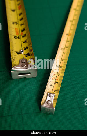 Two tape measures angled on gridded cutting matte Stock Photo