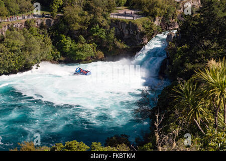 A jet boat with tourists races close to Huka Falls - most visited scenic reserve of New Zealand Stock Photo