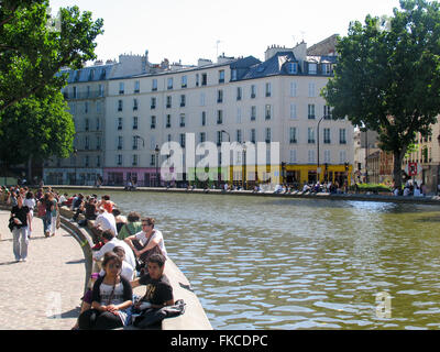 People sitting and enjoying the spring sun along Canal Saint-Martin, Paris. Stock Photo
