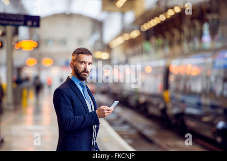 Hipster businessman with smartphone, waiting, train platform Stock Photo