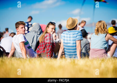 Teenagers at summer music festival, sitting on the grass Stock Photo