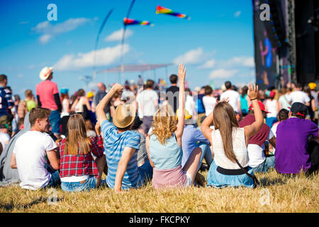 Teenagers, summer music festival, sitting in front of stage Stock Photo