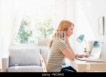 Side-view of young woman working on laptop at home Stock Photo