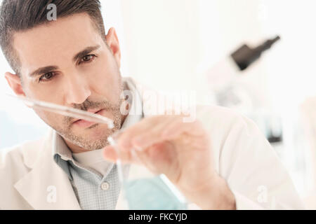 Man pouring liquid into conical flask Stock Photo