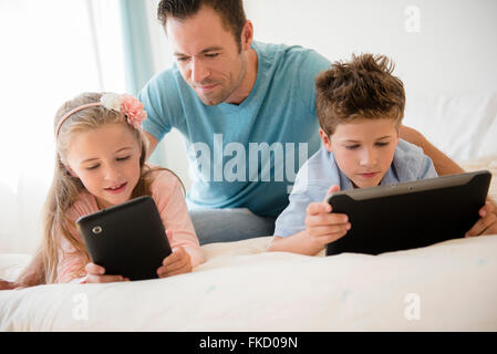 Father with son (8-9) and daughter (6-7) using tablets Stock Photo