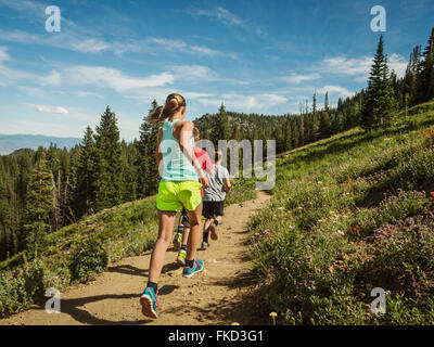 Three children (10-11, 12-13, 14-15) running in mountains Stock Photo