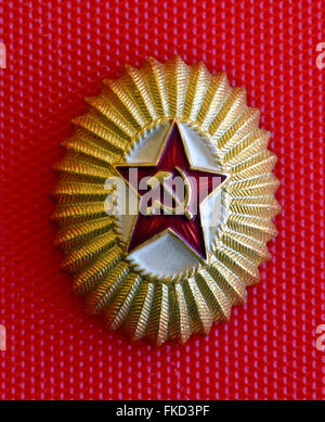 A popular badge of the Soviet Union shows a red star with the hammer and sickle, a Communist symbol created for the Russian Revolution of 1917. It was given to an American visitor in the USSR (Union of the Soviet Socialist Republics) in 1962 during the Cold War. This oval lightweight metal emblem measures 1-3/16 inches in the short dimension by 1-7/16 inches in the long dimension. Stock Photo