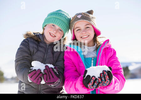 Portrait of girls (8-9, 10-11) holding snow Stock Photo