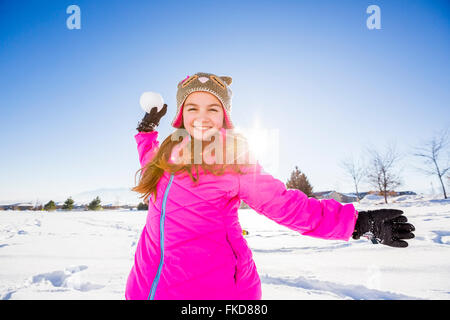 Girl (10-11) in pink jacket throwing snowball Stock Photo