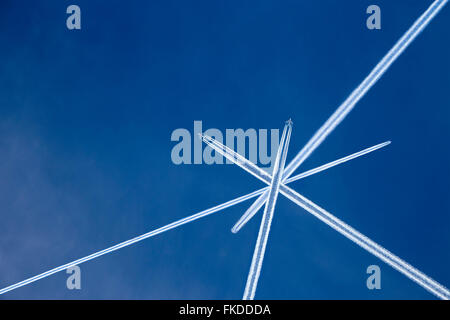 Crossed vapor trails of airplanes in blue sky Stock Photo