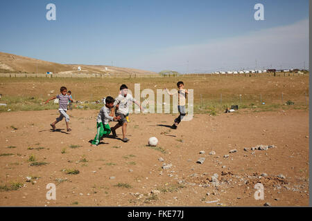 Young yezidi boys playing football in a refugee camp outside the city of  Duhok, Iraqi Kurdistan Stock Photo